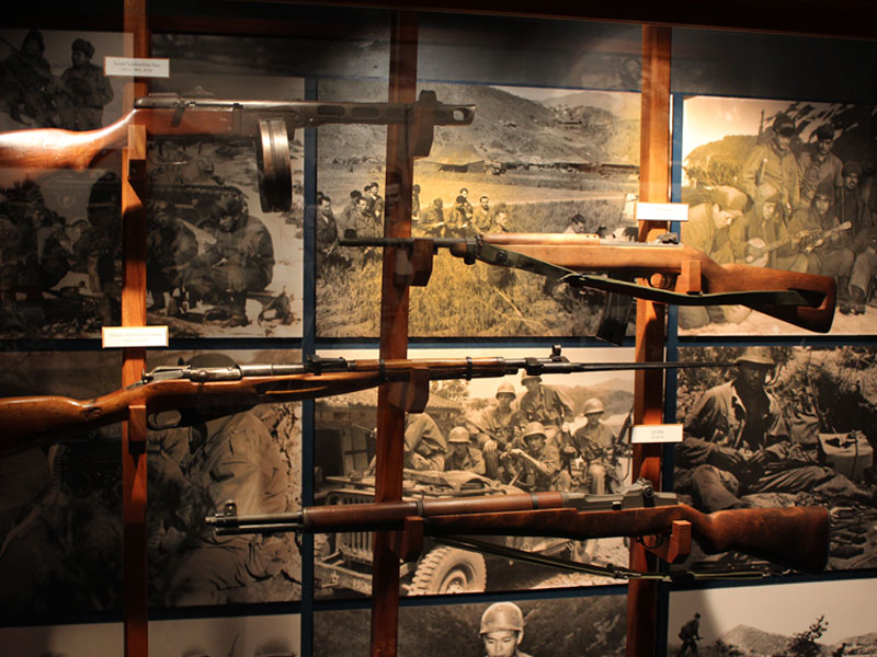 Four rifles on wall display inside US Army Museum of Hawaii.